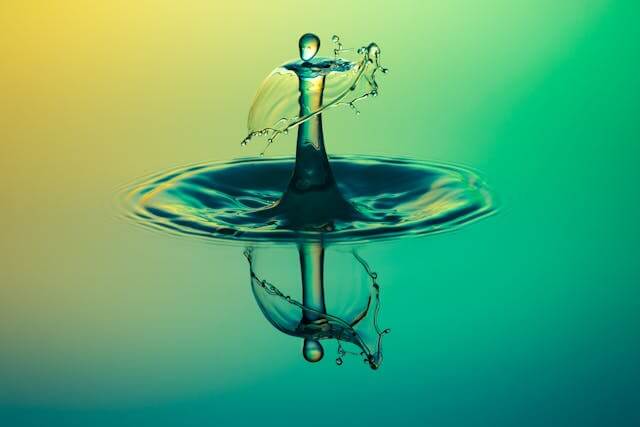 This example shows how a JPEG with a continuous background color gradient and a falling droplet is converted into a GIF. Since JPEGs can display the full RGB color spectrum, including smooth gradients and color transitions with minimal quantization artifacts, the original image looks very fluid. However, in the GIF, which is restricted to only 8-bit color spectrum, the gradient becomes slightly patchy, with groups of similar pixels merging into the same solid color zones, called banding and posterization. (Source: Pexels.)